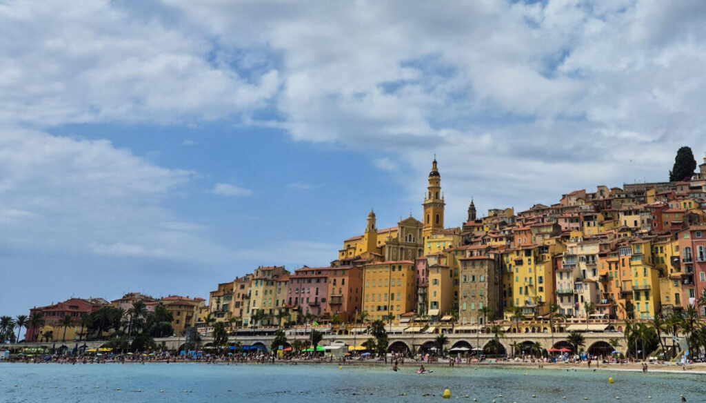 View of Menton during July; view of the coloured buildings in front of the sea.